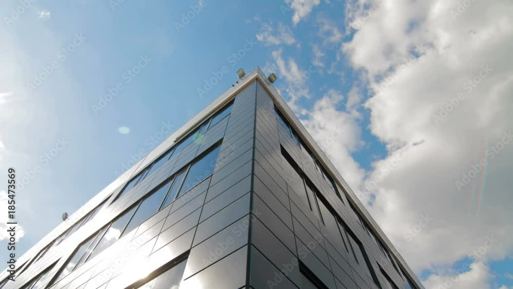 Timelapse of clouds reflected in mirrored facets of modern office building