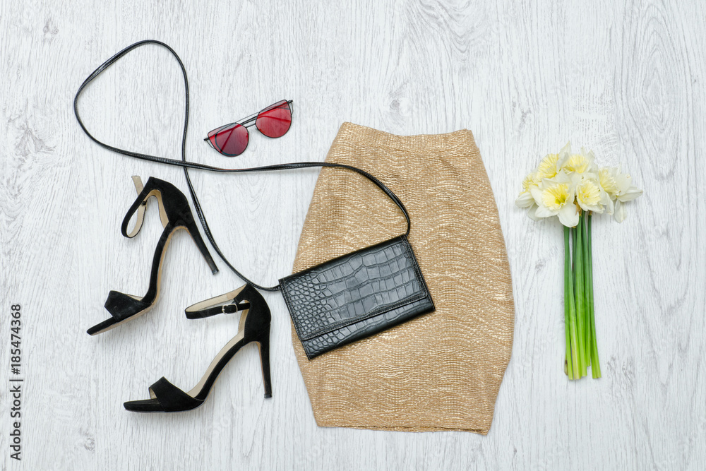 Golden skirt, shoes, glasses and a bouquet of daffodils. Fashionable concept. Wooden background. Golden skirt, shoes, glasses and a bouquet of daffodils. Fashionable concept. Wooden background.