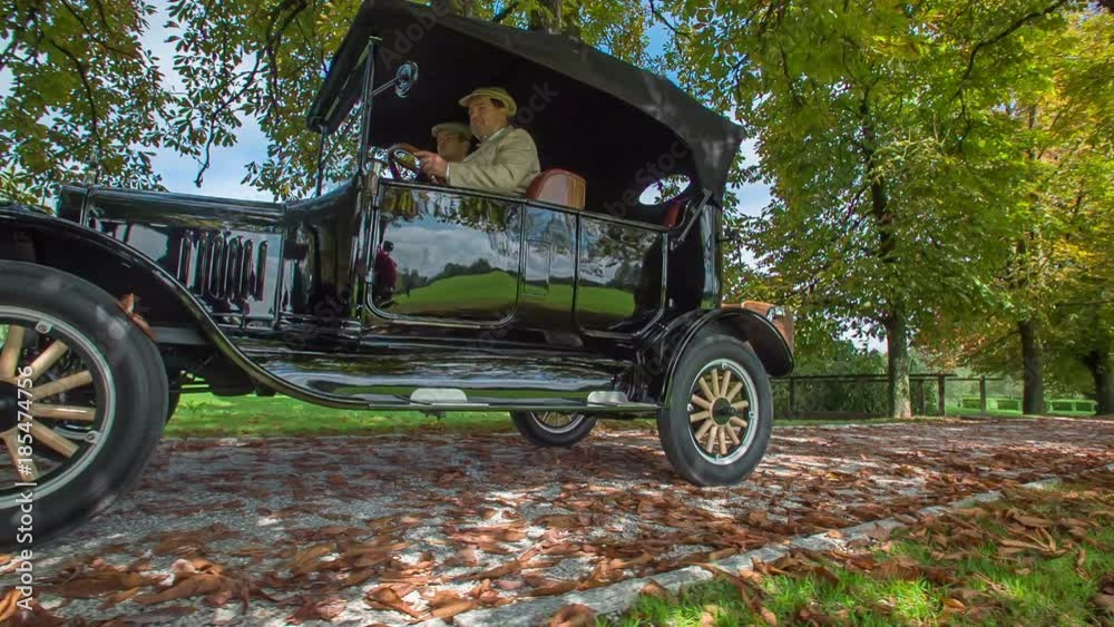 Elegantly dressed driver behind the steering wheel driving special wooden car Ford model T, that originates from USA.