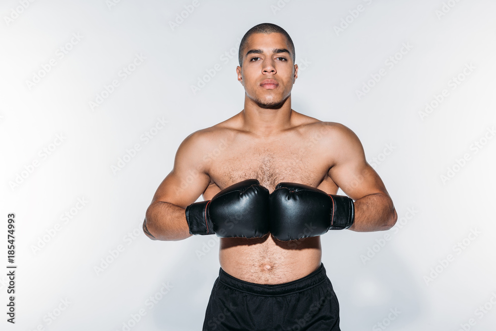 shirtless african american boxer standing with gloves and looking at camera shirtless african american boxer standing with gloves and looking at camera