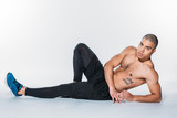 shirtless tattooed african american sportsman lying on floor and looking at camera
