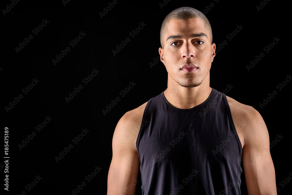 Fototapeta premium handsome sportive african american man looking at camera isolated on black