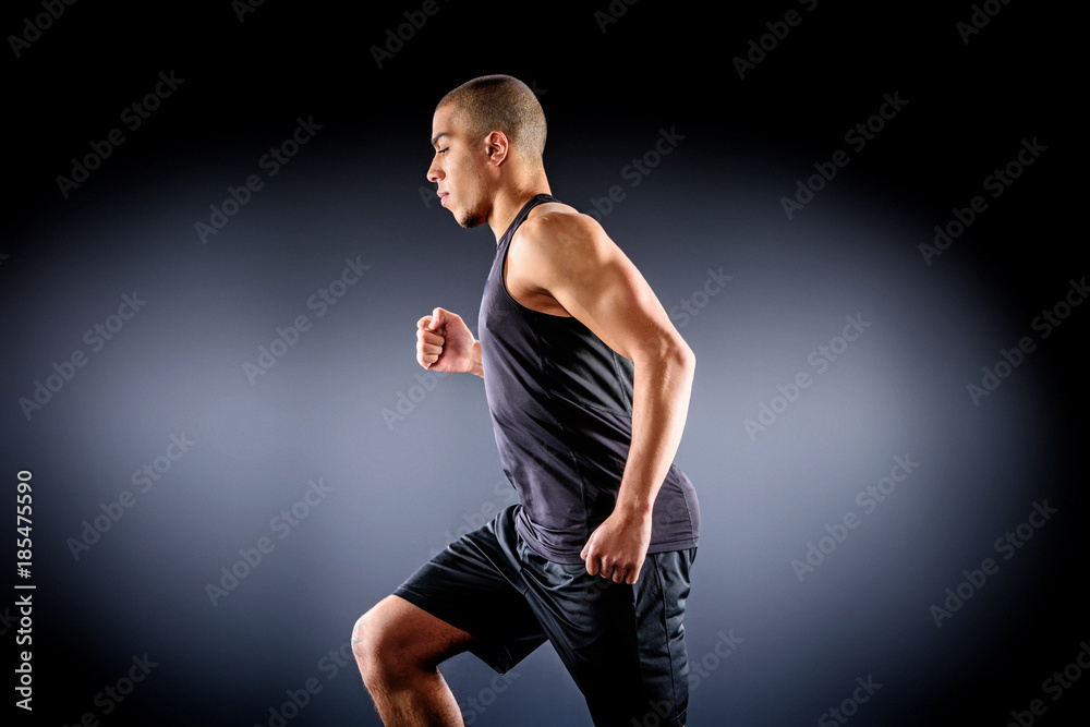side view of african american sportsman running on black side view of african american sportsman running on black