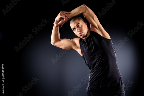 handsome african american sportsman doing side bend before training on black