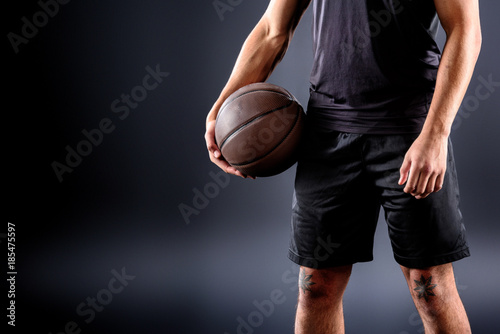 cropped shot of basketball player holding ball on black © LIGHTFIELD STUDIOS