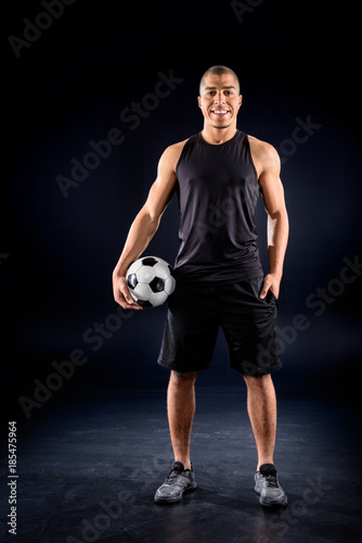 happy african american soccer player with ball on black © LIGHTFIELD STUDIOS