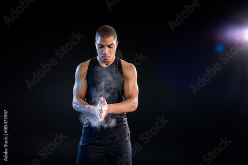 handsome african american sportsman clapping hands with talc on black