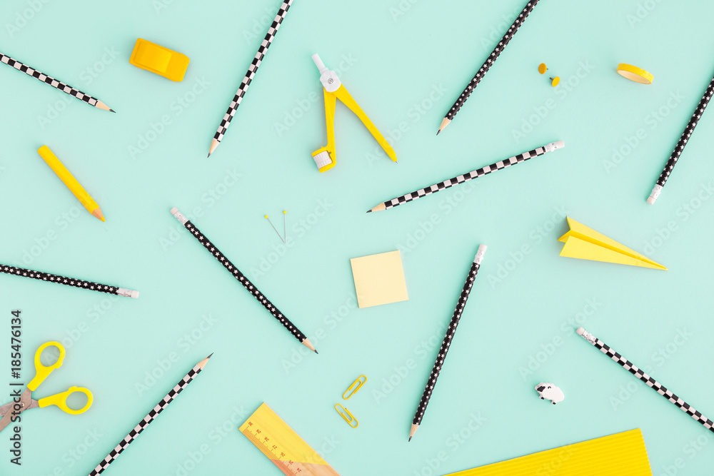 School or office workspace with variety of yellow supplies on cyan background. Flat lay. School or office workspace with variety of yellow supplies on cyan background. Flat lay.