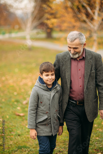 Grandpa and his grandson spend time together in the park. They are sitting on the bench. Walking in the park and rejoicing © Aleksandr