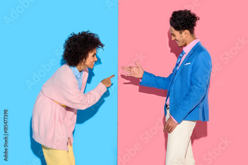 Happy couple gesturing and making funny shadows on pink and blue background