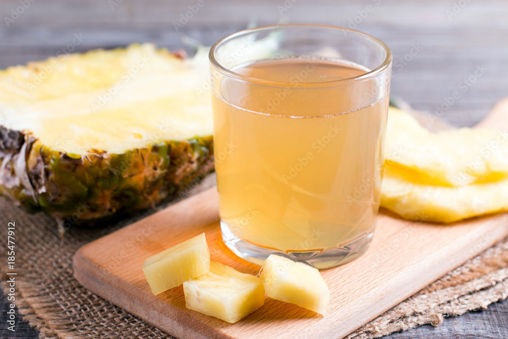 Pineapple juice in a glass on a cutting board
