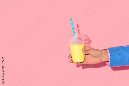 Cropped shot of african american man holding glass of juice on pink background