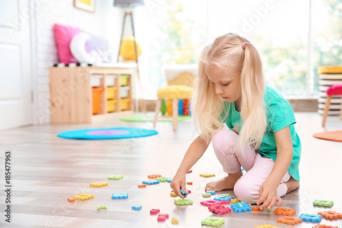 Cute little girl playing with math puzzle at home