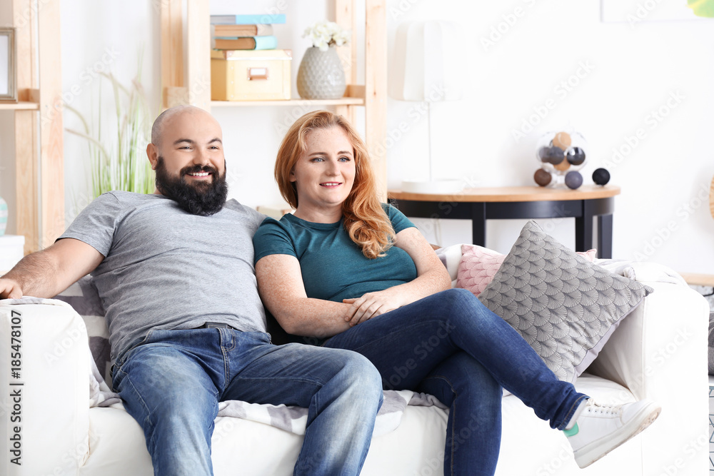 Overweight couple watching tv at home