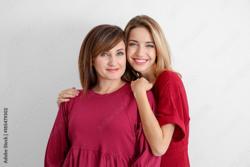 Attractive young woman with her mother in matching dresses on white background Attractive young woman with her mother in matching dresses on white background
