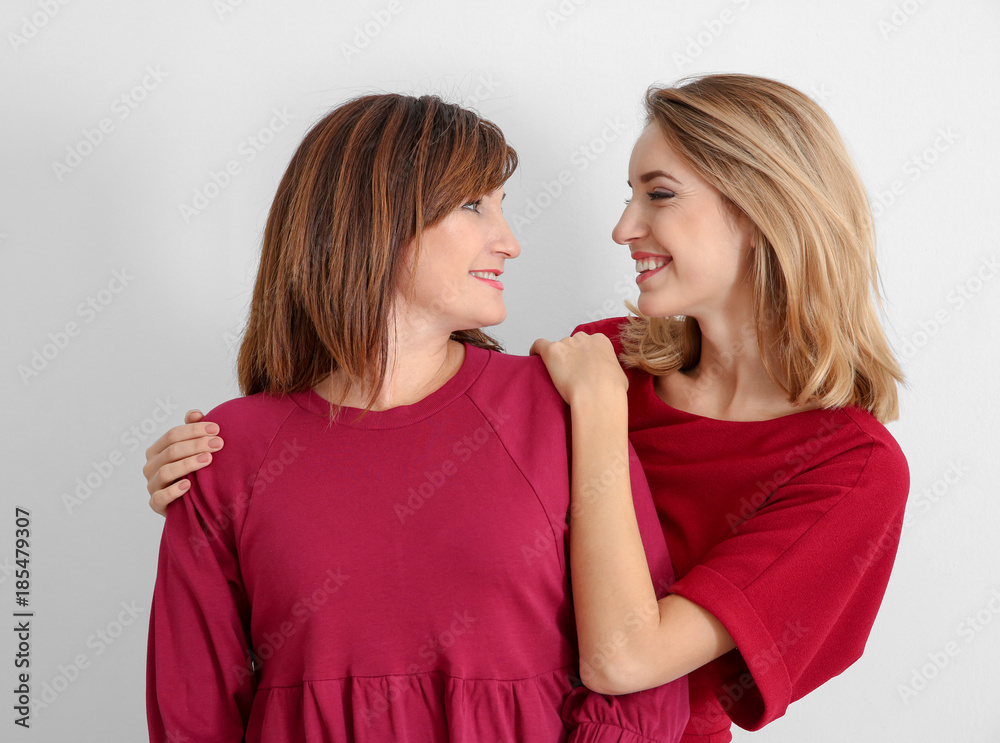 Attractive young woman with her mother in matching dresses on white background Attractive young woman with her mother in matching dresses on white background