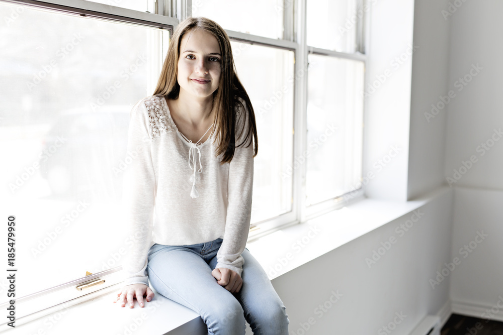 Teenager girl sitting on window Teenager girl sitting on window
