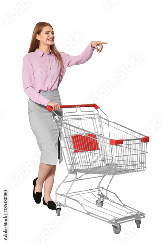 Young woman with empty shopping cart on white background