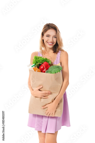 Young woman holding paper bag with groceries on white background © Africa Studio