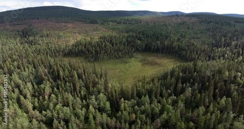 Drone flight over finlands forest with glade and moorland