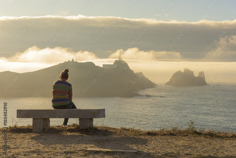 Girl sitting in front of Vilan cape (Camarinas, La Coruna - Spain).