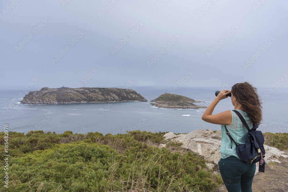 Girl with binoculars looking at Sisarga Islands (Malpica, La Coruna - Spain).