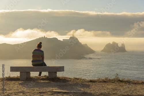 Girl sitting in front of Vilan cape (Camarinas, La Coruna - Spain).