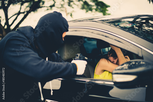 Fotografi Criminal or Bandit wear black mask use gun point to woman in black car at the pa