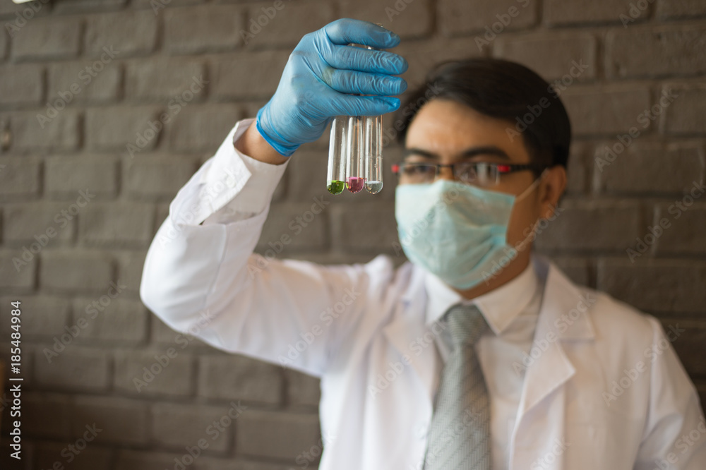scientist wear white dress and blue gloves holding multicolor glass test tube. Chemist examines chemical test tube, science, doctor scientist wear white dress and blue gloves holding multicolor glass test tube. Chemist examines chemical test tube, science, doctor