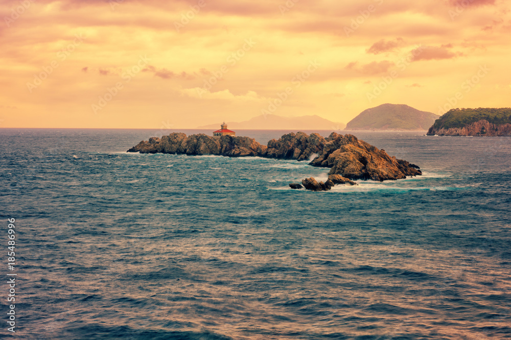Rocky island Greben with lighthouse in the Adriatic sea, sunset seascape, Dubrovnik, Croatia