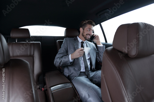 businessman sitting in car with cup and smartphone