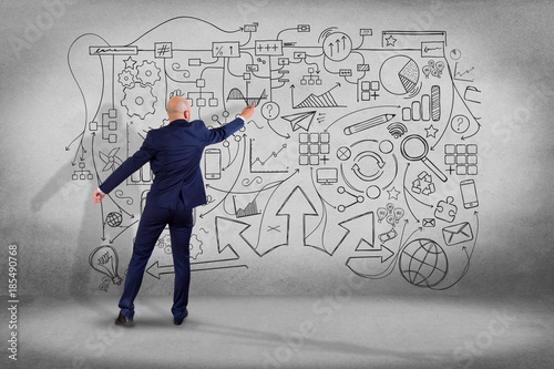 Businessman drawing a hand drawn Complex schema on a wall - network and communication concept