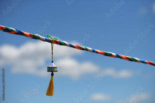 colorful prayer ropes and wind chimes fluttering in the wind and blue sky
 photo