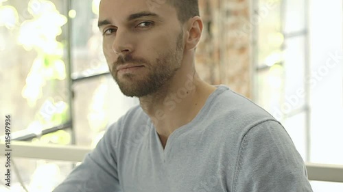 Handsome man in blue sweater sitting in the cafe and showing thumbs up to the camera, steadycam shot
 photo