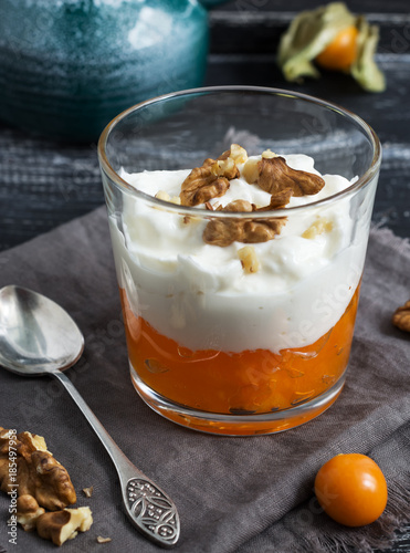 Yogurt with orange fruit jam with walnut on a napkin, vintage spoon and fruits of physalis.