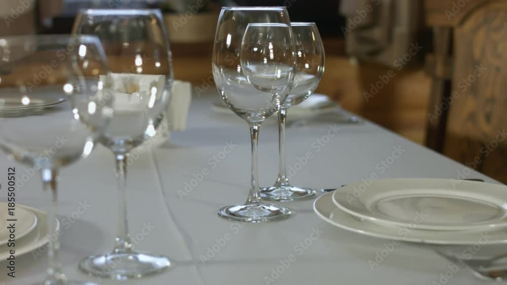 The waiter puts the glasses on the table in the restaurant The waiter puts the glasses on the table in the restaurant