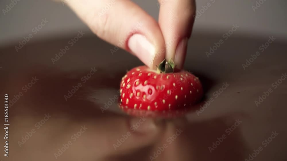 Hand dipping strawberry in melted chocolate Full HD slow motion close-up video. Fresh berries sweet dessert food background