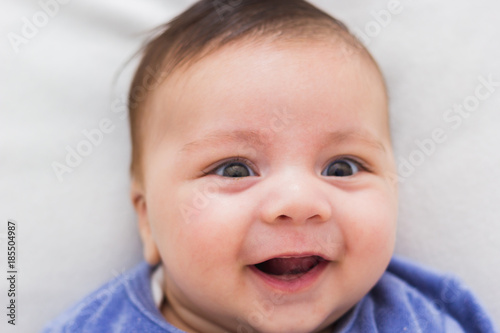 close up of smiling baby lying in his crib