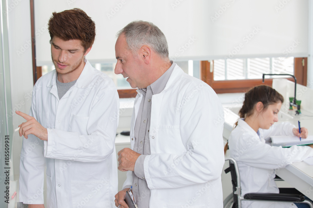 male scientific researcher drawing on blank blackboard in laboratory male scientific researcher drawing on blank blackboard in laboratory