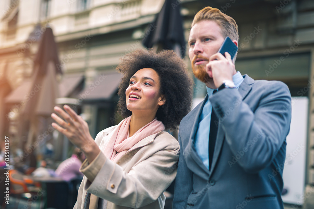 Two business people in an informal conversation in front of a business building Two business people in an informal conversation in front of a business building