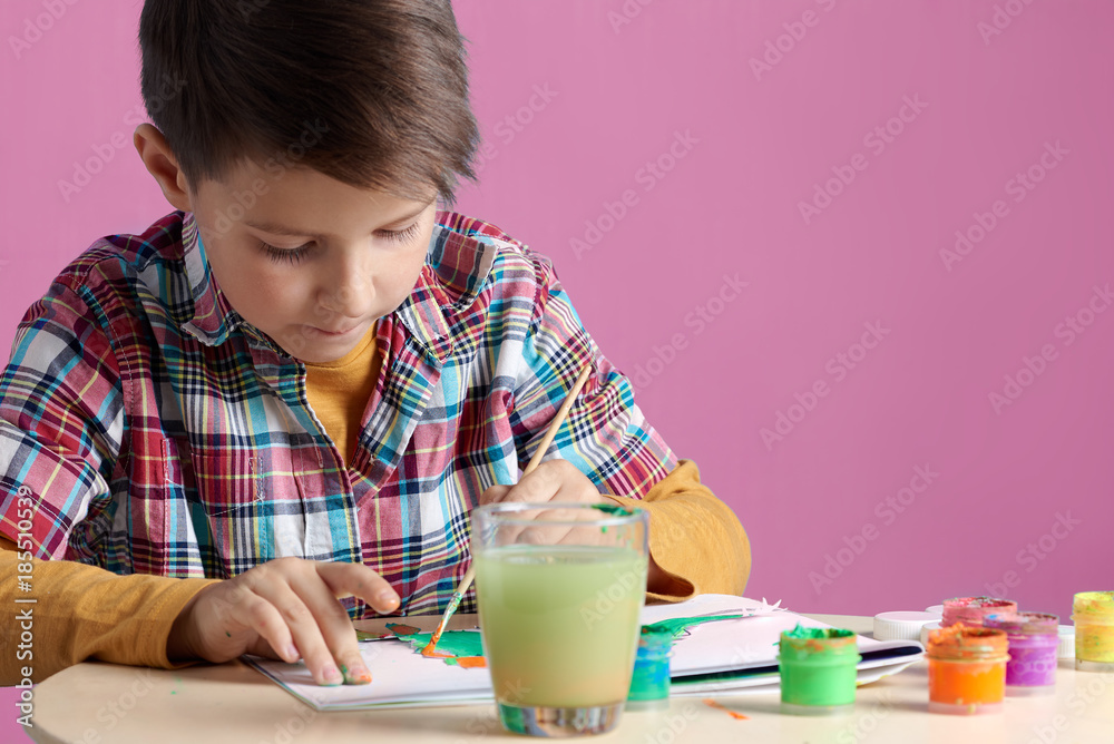 Caucasian boy is carefully painting with watercolors. Caucasian boy is carefully painting with watercolors.