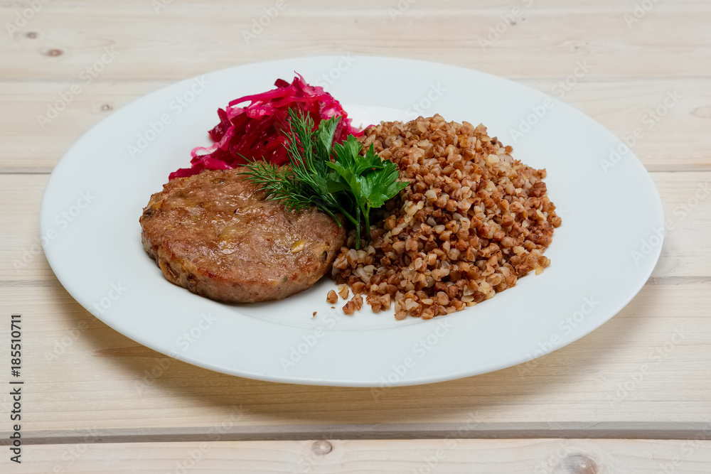 Portion of fried beef cutlet, boiled buckwheat and pickled red cabbage Portion of fried beef cutlet, boiled buckwheat and pickled red cabbage