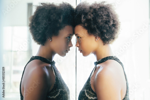 Young woman looking at reflection in mirror photo