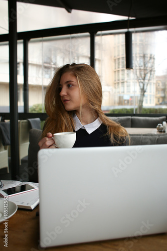 woman in a cafe with a cup with a laptop business