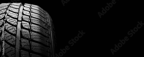 car winter tyre on black  background. vehicle wheel pneumatic photo