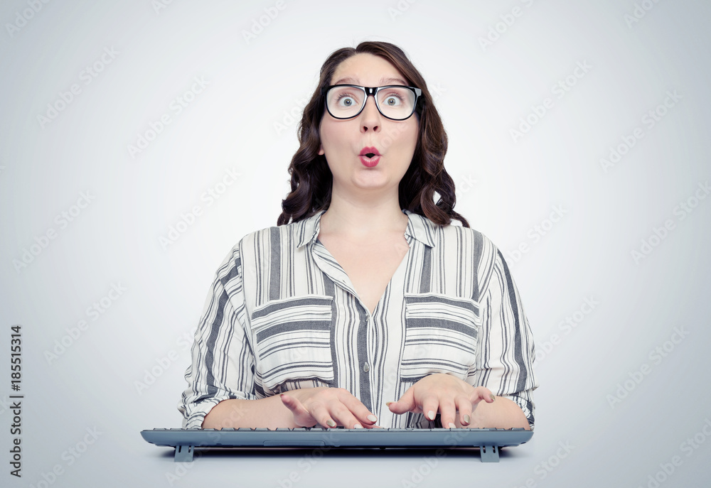 Funny girl programmer in glasses with keyboard in front of computer Funny girl programmer in glasses with keyboard in front of computer