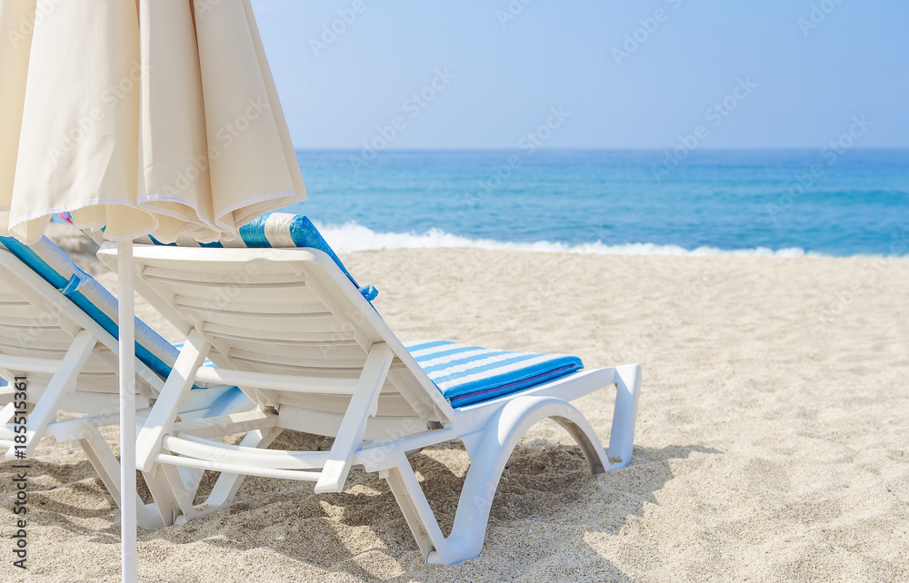 Sun umbrella and chaise longue on sea beach. White sand and sea in tropical resort. The concept of beach holiday. Relax and vacation. Sun umbrella and chaise longue on sea beach. White sand and sea in tropical resort. The concept of beach holiday. Relax and vacation.
