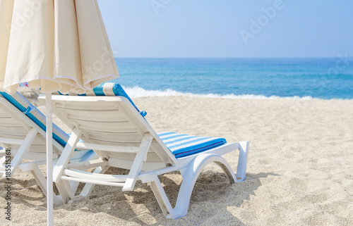 Fototapeta Naklejka Na Ścianę i Meble -  Sun umbrella and chaise longue on sea beach. White sand and sea in tropical resort. The concept of beach holiday. Relax and vacation.