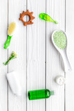 Children's means hygiene with chamomile. Bottles, spa salt, tooth brush and toy on white wooden background top view copyspace