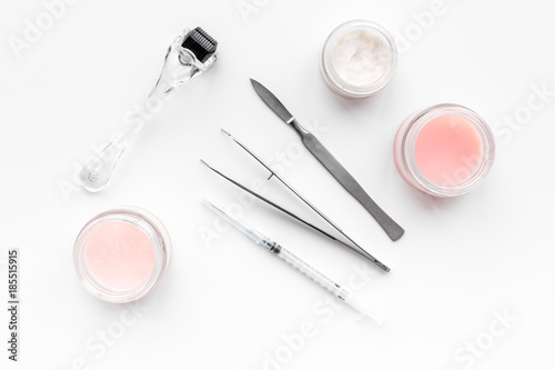 Dermatologist or cosmetologist accessories. Dermaroller, creams and mask, beauty injection, tools on white background top view